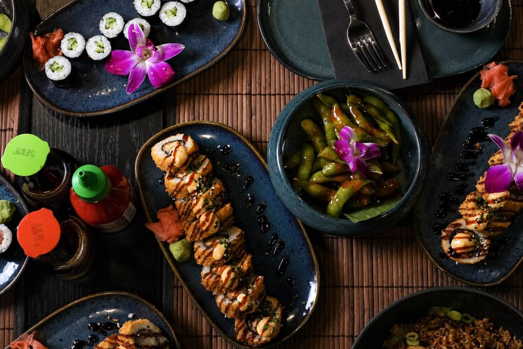 Overzicht van verschillende sushi-gerechten en edamame op tafel.